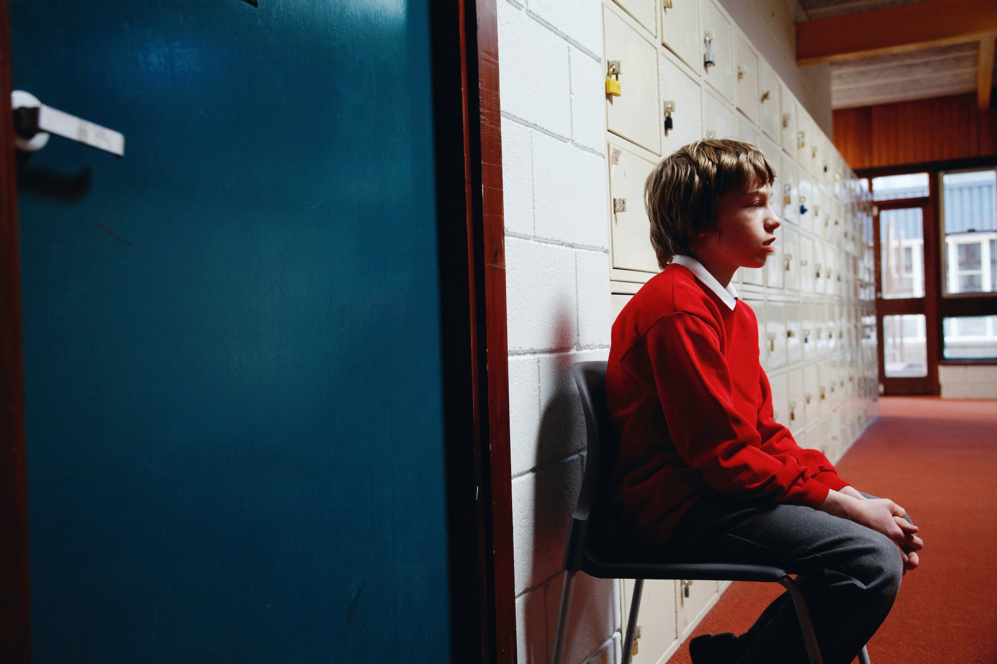 schoolboy sitting on chair in corridor